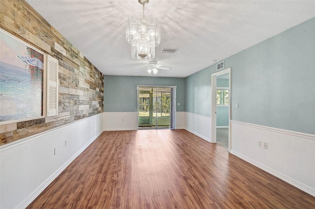 602 Park Cir, Bradenton, FL 34207 - spare room with a textured ceiling, a chandelier, wood finished floors, a ceiling fan, and a wainscoted wall