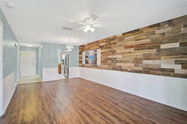 602 Park Cir, Bradenton, FL 34207 - unfurnished room featuring a ceiling fan, wooden walls, a chandelier, wood finished floors, and a textured ceiling
