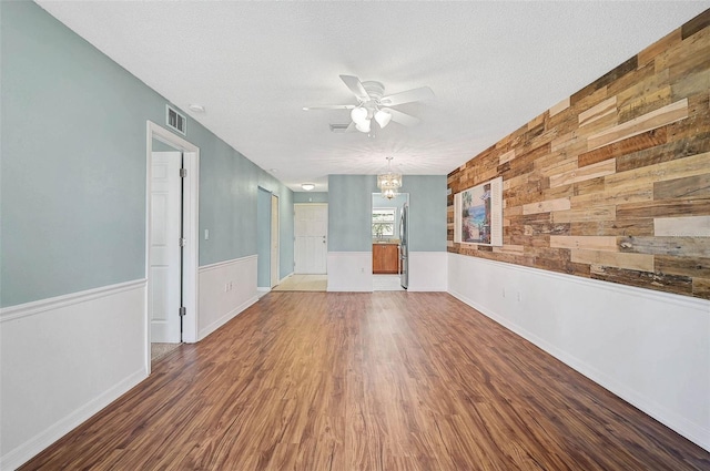 602 Park Cir, Bradenton, FL 34207 - spare room with a ceiling fan, wooden walls, wood finished floors, a textured ceiling, and a chandelier