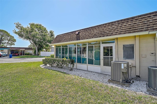 602 Park Cir, Bradenton, FL 34207 - back of house featuring cooling unit, a sunroom, roof with shingles, and a yard