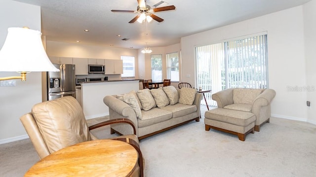 living room with plenty of natural light, ceiling fan, baseboards, and light carpet