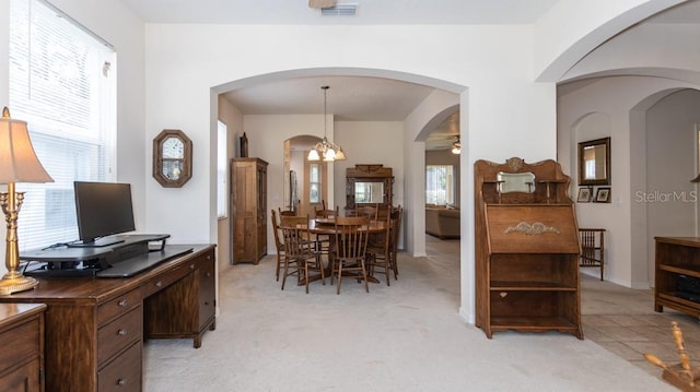 dining room with light carpet, arched walkways, and ceiling fan