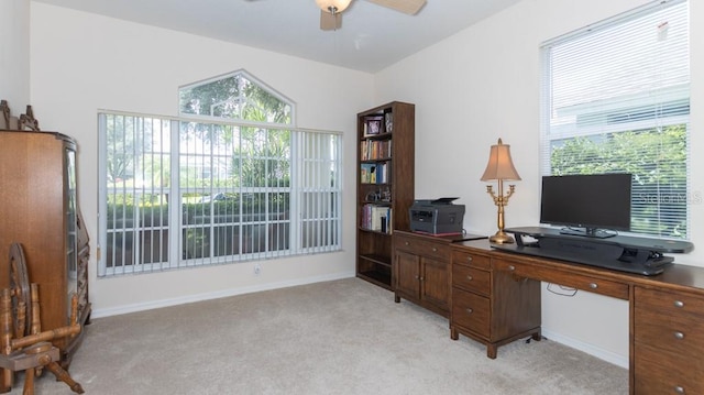office space featuring light colored carpet, a ceiling fan, and baseboards