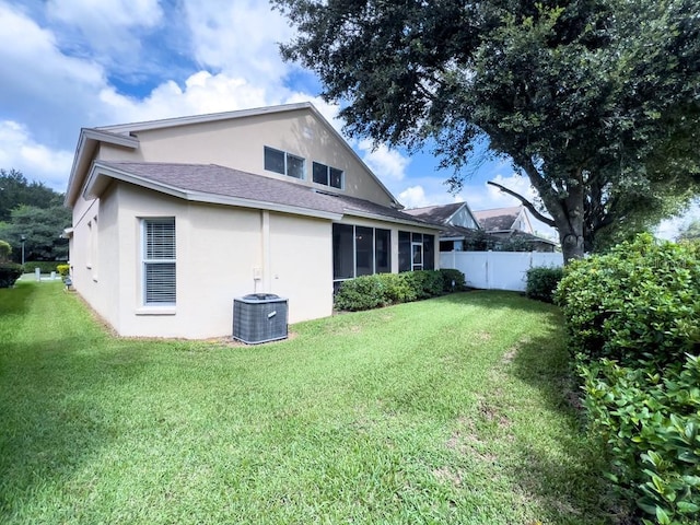 rear view of property featuring stucco siding, central AC unit, roof with shingles, and a sunroom