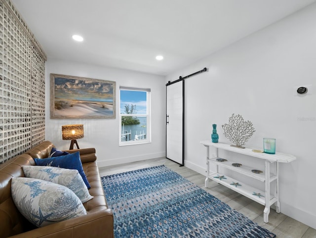 sitting room with a barn door, baseboards, wood finished floors, and recessed lighting
