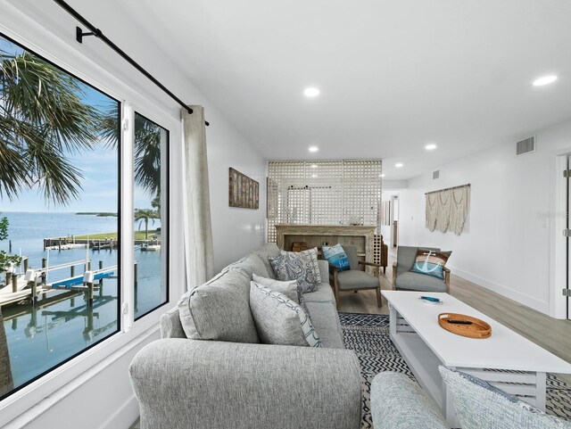 living area featuring wood finished floors, a water view, recessed lighting, and baseboards