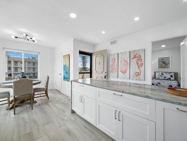kitchen featuring light stone counters, white cabinetry, recessed lighting, light wood-type flooring, and baseboards