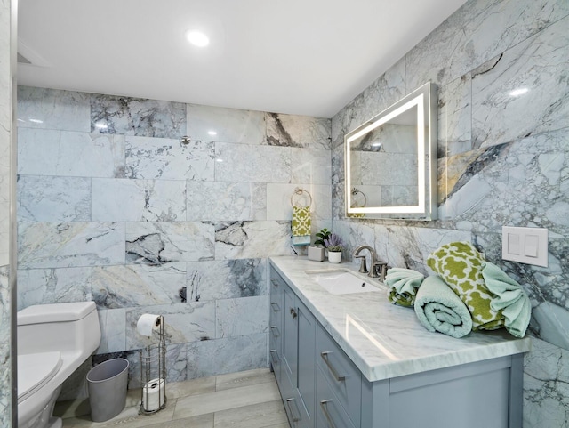 bathroom with tile walls, toilet, and vanity