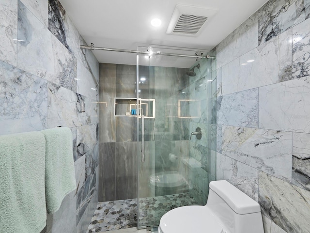bathroom featuring tile walls, a stall shower, and toilet