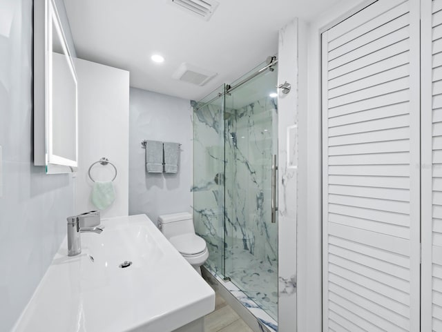bathroom with toilet, a marble finish shower, recessed lighting, and a sink