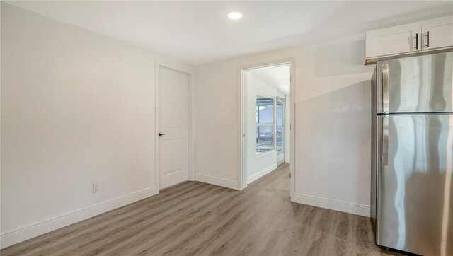 1227 Porpoise Rd, Venice, FL 34293 - kitchen with freestanding refrigerator, light wood-style flooring, baseboards, white cabinetry, and recessed lighting