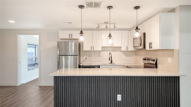 1227 Porpoise Rd, Venice, FL 34293 - kitchen with stainless steel appliances, a sink, baseboards, light wood-style flooring, and a peninsula