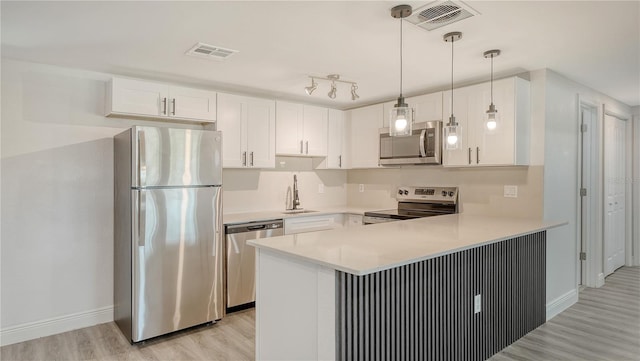 1227 Porpoise Rd, Venice, FL 34293 - kitchen featuring appliances with stainless steel finishes, a sink, light wood-style floors, a peninsula, and white cabinets