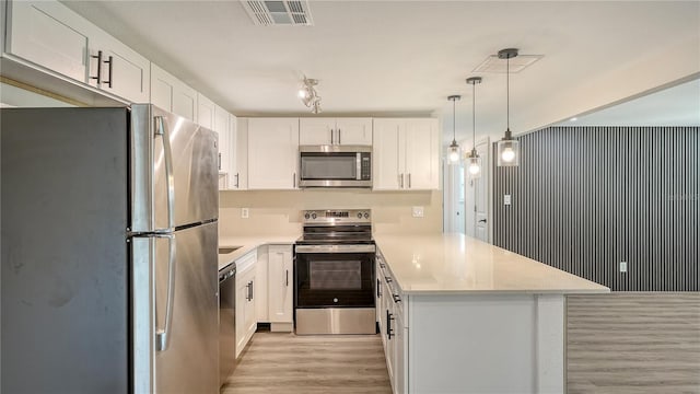 1227 Porpoise Rd, Venice, FL 34293 - kitchen featuring appliances with stainless steel finishes, a peninsula, light wood-style flooring, light countertops, and white cabinetry