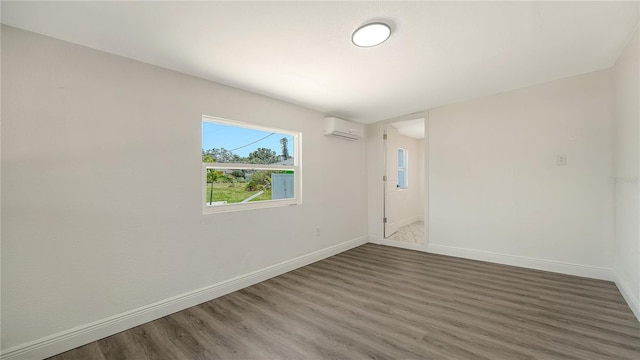 1227 Porpoise Rd, Venice, FL 34293 - empty room featuring an AC wall unit, wood finished floors, and baseboards