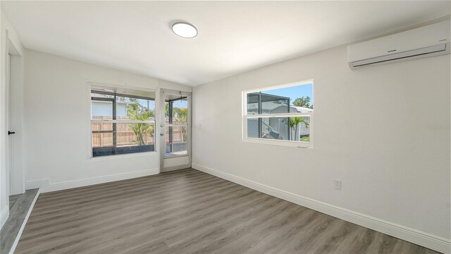 1227 Porpoise Rd, Venice, FL 34293 - empty room featuring a wall mounted air conditioner, healthy amount of natural light, and baseboards
