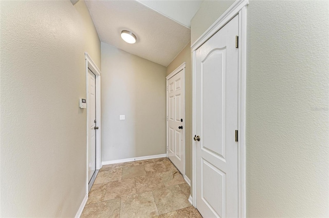 hall featuring baseboards and light stone finish flooring