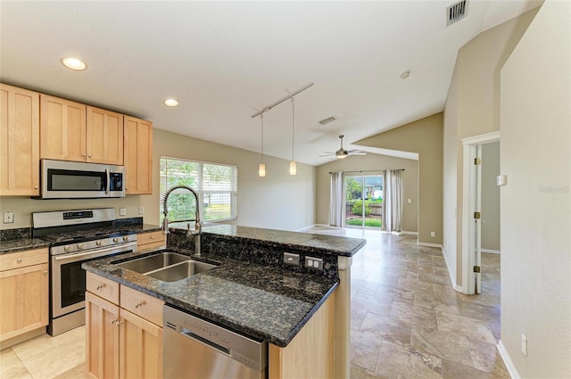kitchen featuring stainless steel appliances, light brown cabinets, a sink, healthy amount of natural light, and lofted ceiling