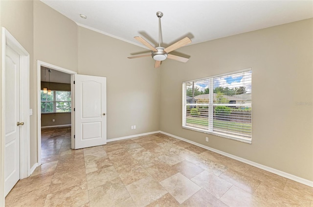 spare room featuring a ceiling fan, baseboards, and light stone finish floors