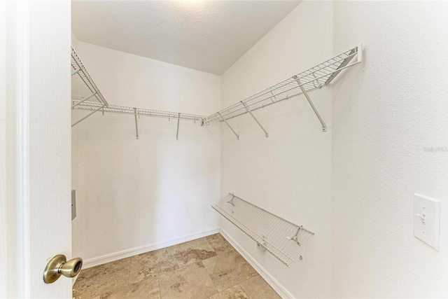 spacious closet featuring light stone finish floors