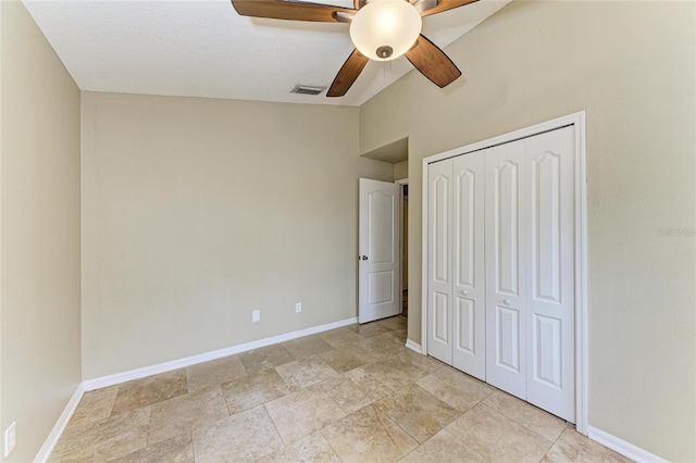 unfurnished bedroom featuring baseboards, a closet, vaulted ceiling, ceiling fan, and light stone finish floors