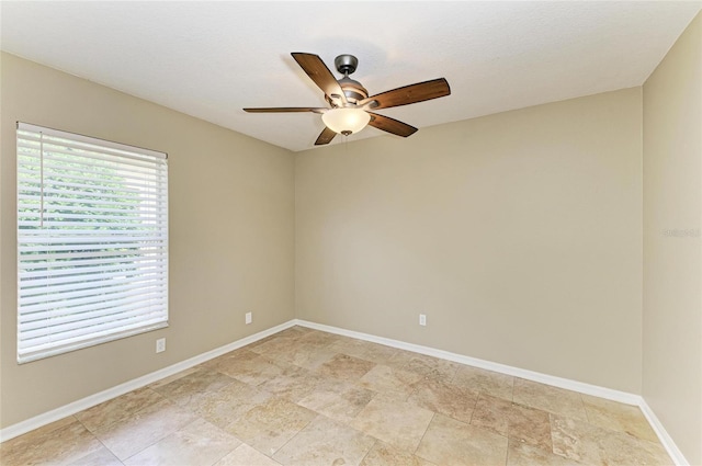 empty room with a ceiling fan and baseboards
