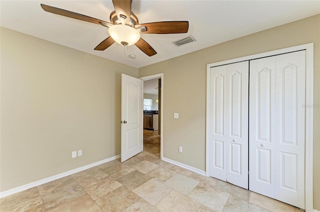 unfurnished bedroom with baseboards, light stone finish floors, a closet, and a ceiling fan