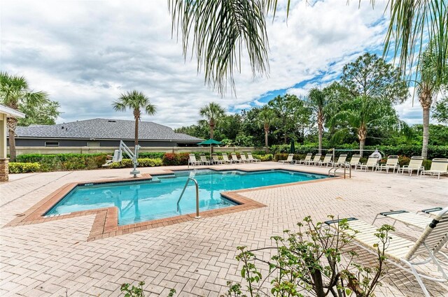 community pool with a patio area and fence