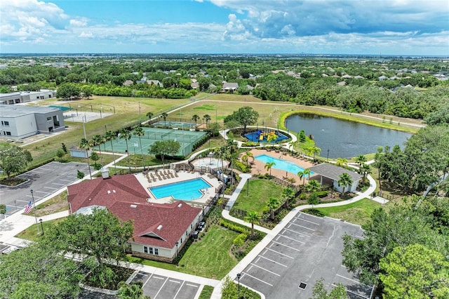 bird's eye view of a pool, a tree filled landscape, and a large body of water
