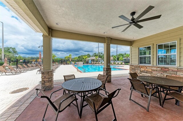 view of patio with fence, ceiling fan, and a community pool