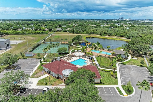 aerial view of a pool, a tree filled landscape, and a nearby body of water