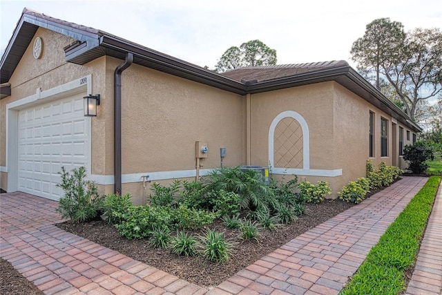 12091 Firewheel Pl, Venice, FL 34293 - view of side of property with an attached garage, stucco siding, and driveway
