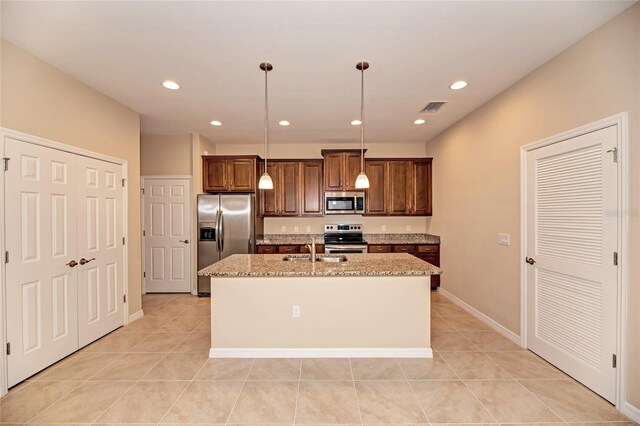 12091 Firewheel Pl, Venice, FL 34293 - kitchen with stainless steel appliances, a sink, a kitchen island with sink, light stone counters, and decorative light fixtures