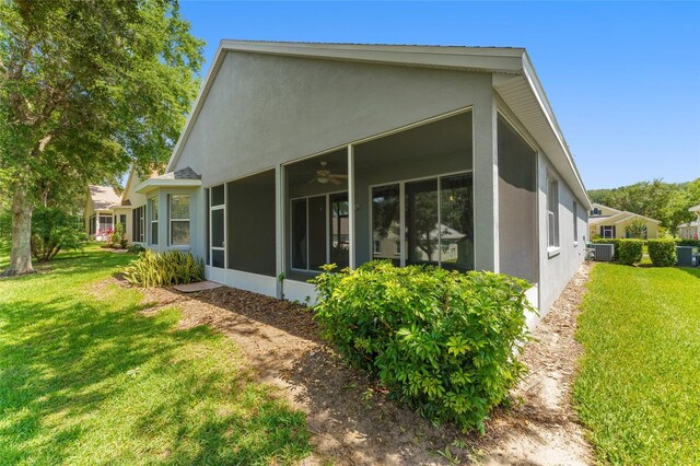 777 Summit Greens Blvd, Clermont, FL 34711 - view of property exterior with a sunroom, stucco siding, central air condition unit, and a lawn