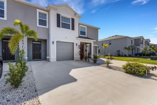 view of front of home featuring stucco siding, concrete driveway, a garage, and a residential view