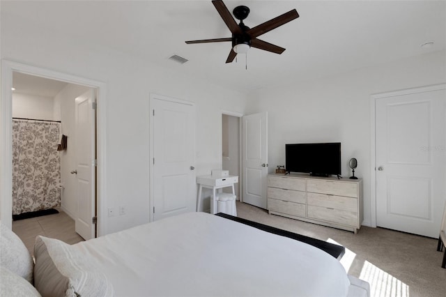 bedroom featuring ceiling fan, baseboards, light carpet, and ensuite bathroom
