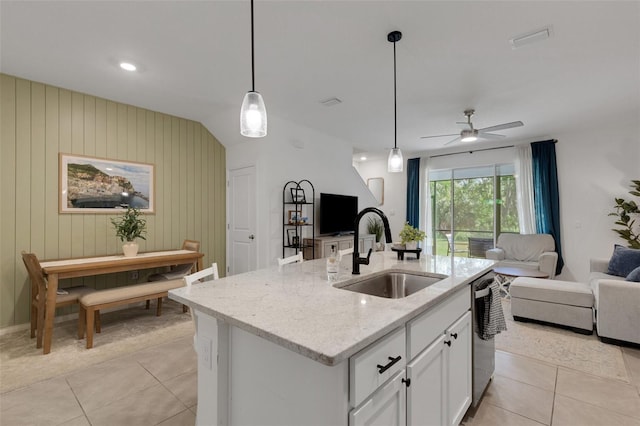 kitchen featuring a sink, open floor plan, light tile patterned floors, light stone counters, and vaulted ceiling