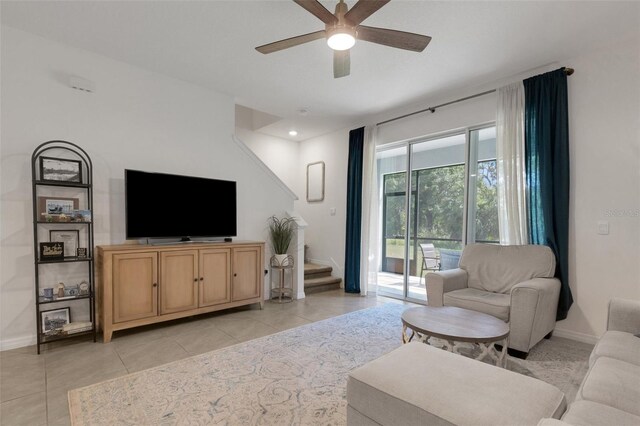 living area with a ceiling fan, light tile patterned floors, stairway, and baseboards