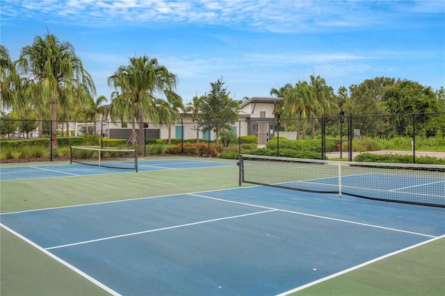 view of tennis court with community basketball court and fence