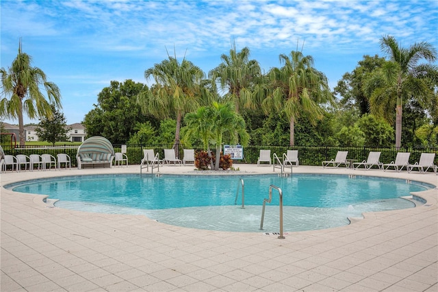 community pool with fence and a patio