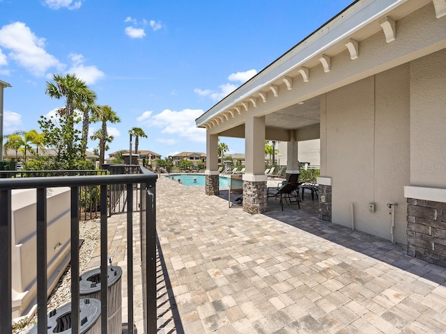 view of patio with a community pool and a balcony