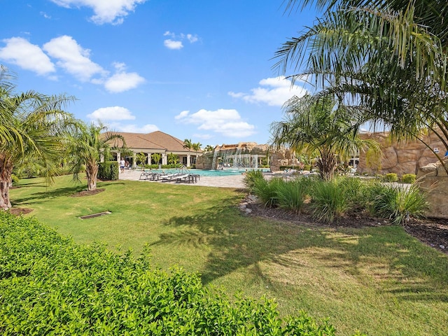 view of green lawn with a community pool and a patio