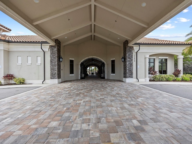 doorway to property featuring stucco siding, a tile roof, and decorative driveway