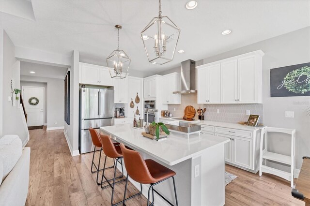 1017 Fernleaf Run, Bradenton, FL 34212 - kitchen with freestanding refrigerator, wall chimney exhaust hood, a chandelier, tasteful backsplash, and a breakfast bar