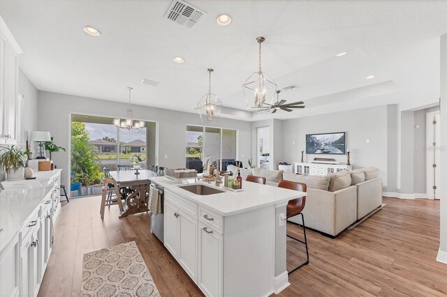 1017 Fernleaf Run, Bradenton, FL 34212 - kitchen featuring a sink, a chandelier, a breakfast bar area, light wood-style flooring, and white cabinets