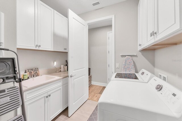 1017 Fernleaf Run, Bradenton, FL 34212 - laundry room featuring washing machine and dryer, cabinet space, and light tile patterned flooring