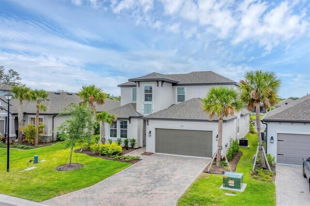 1017 Fernleaf Run, Bradenton, FL 34212 - traditional-style home with stucco siding, an attached garage, decorative driveway, roof with shingles, and a front yard