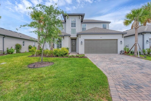 1017 Fernleaf Run, Bradenton, FL 34212 - view of front facade featuring stucco siding, an attached garage, decorative driveway, a front yard, and a shingled roof