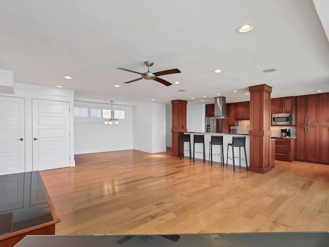 226 Golden Gate Pt Unit 63, Sarasota, FL 34236 - kitchen featuring stainless steel appliances, wall chimney range hood, a kitchen bar, ceiling fan, and recessed lighting