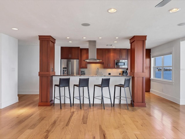226 Golden Gate Pt Unit 63, Sarasota, FL 34236 - kitchen featuring appliances with stainless steel finishes, wall chimney range hood, baseboards, a breakfast bar area, and recessed lighting